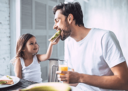 a man with dentures eating a sandwich with his daughter