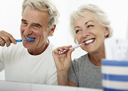 senior man and woman brushing their teeth 